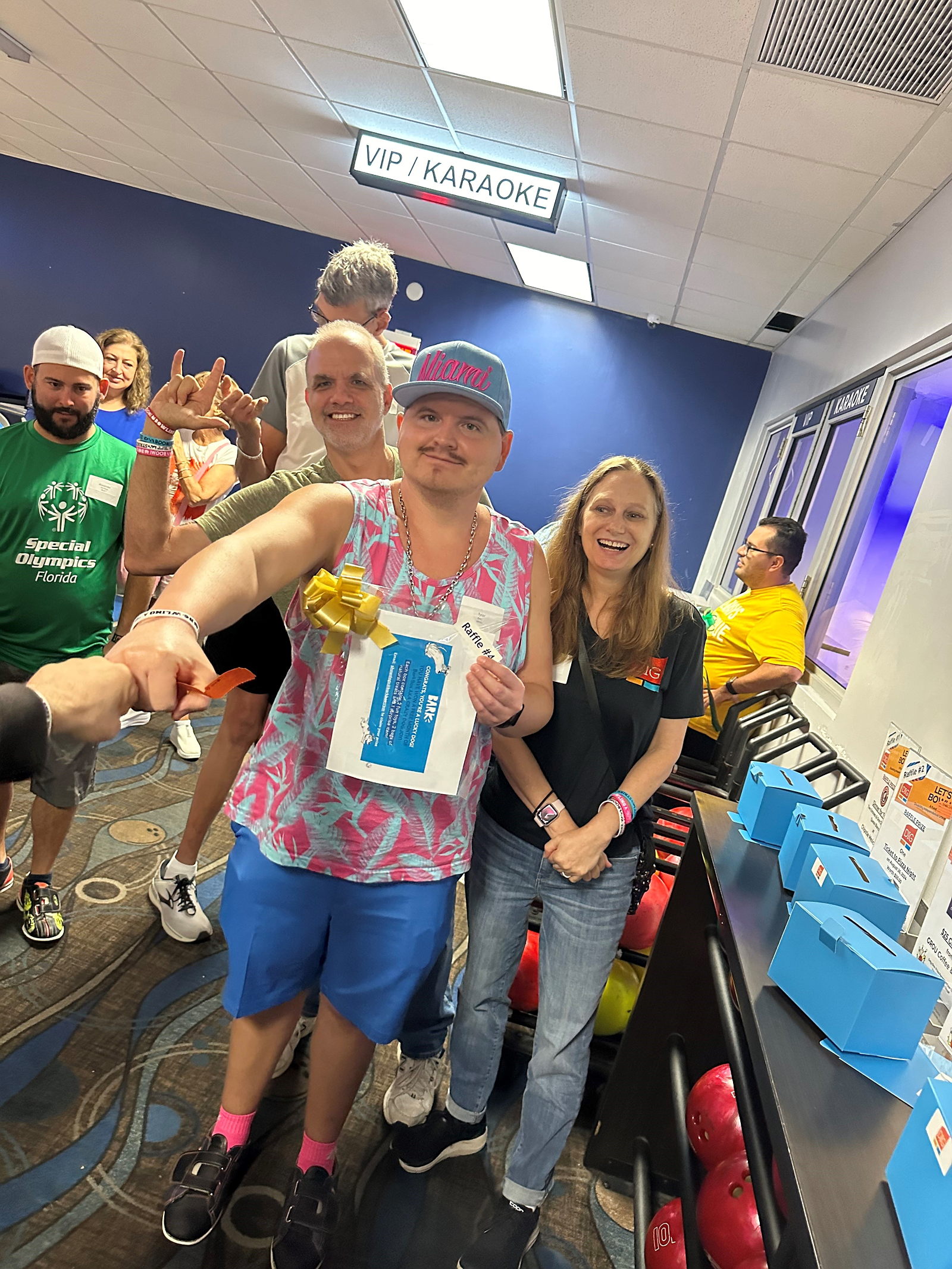 Tyler holding a raffle prize with Debbie and Matt.