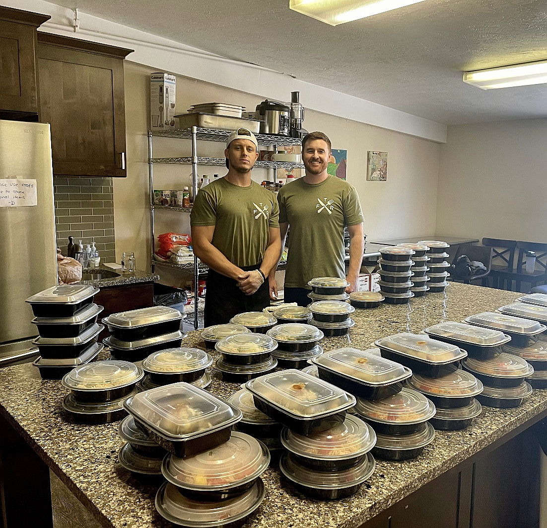 Randy and Bryan cooking in the kitchen, preparing weekly community meal-prep meals.