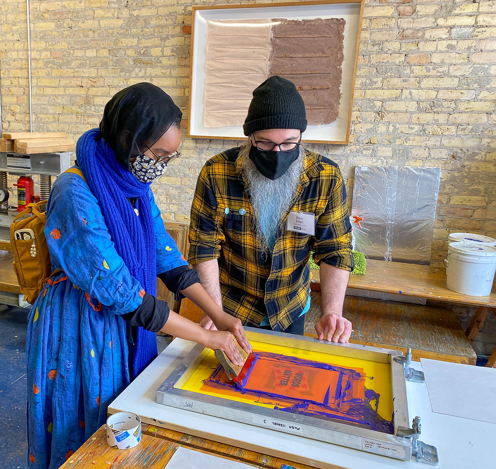 A MCBA instructor and community member engage in a screen printing demonstration at Love Local.