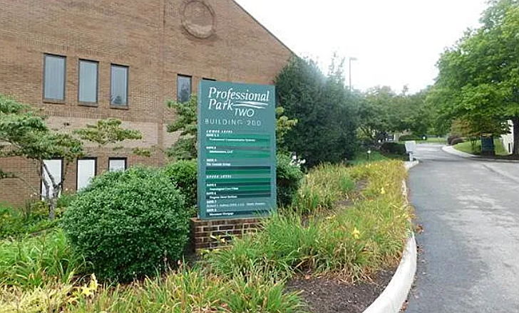Outside an office building a large green sign shares a company directory