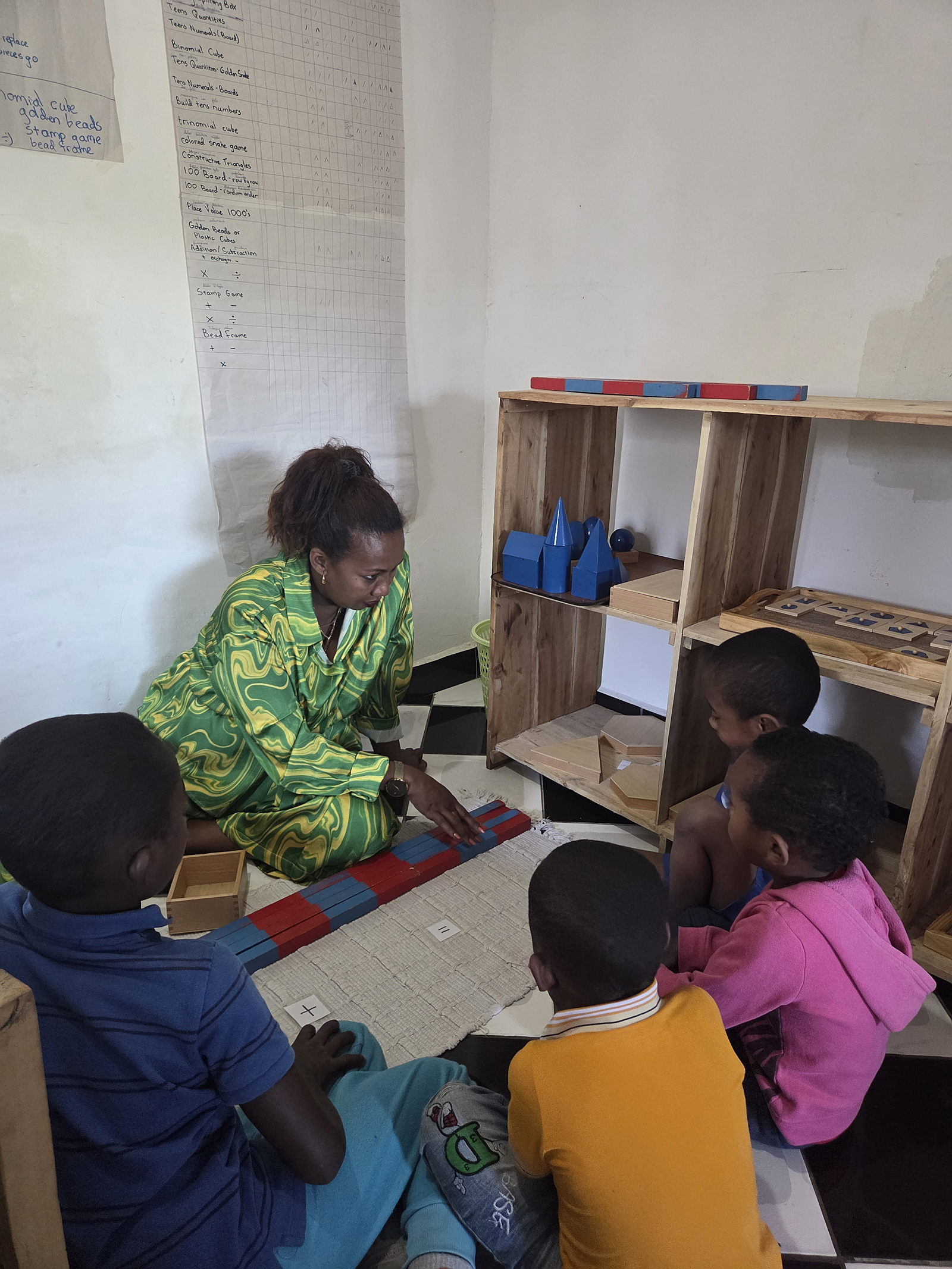 Picture of students working with adult, red and blue rods, addition and subtraction lesson.