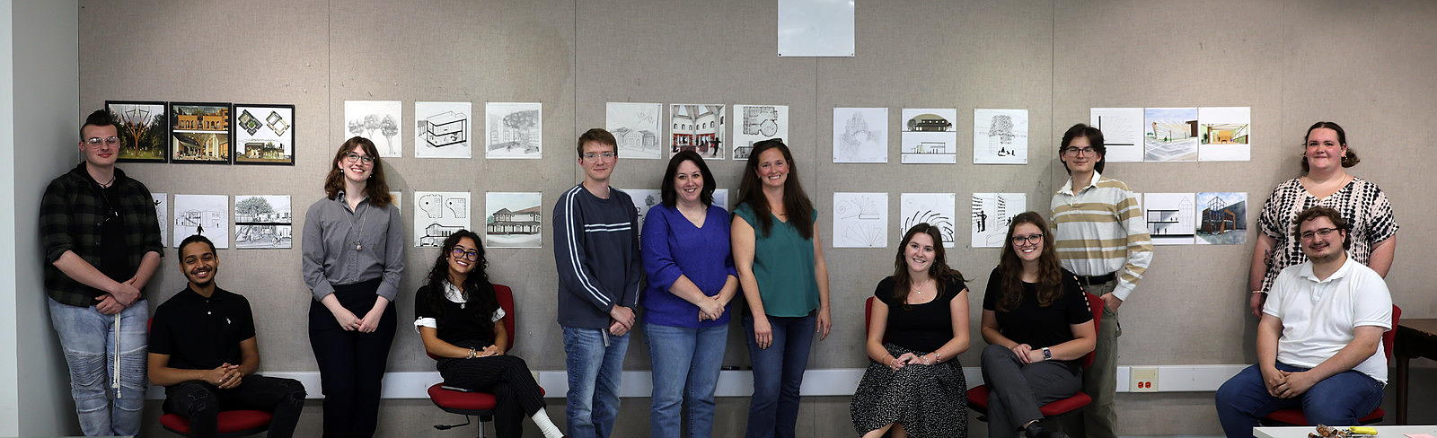 Women pose with college students in front of presentation. 