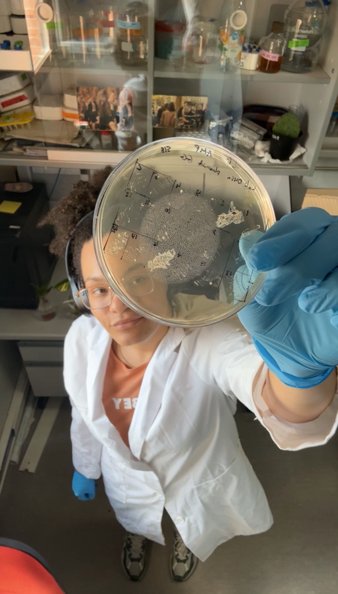 person in lab coat with petri dish