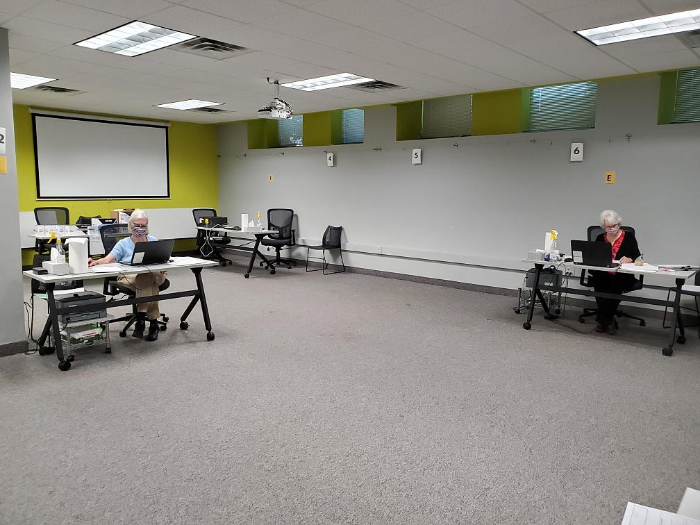 large room with masked volunteers sitting far apart