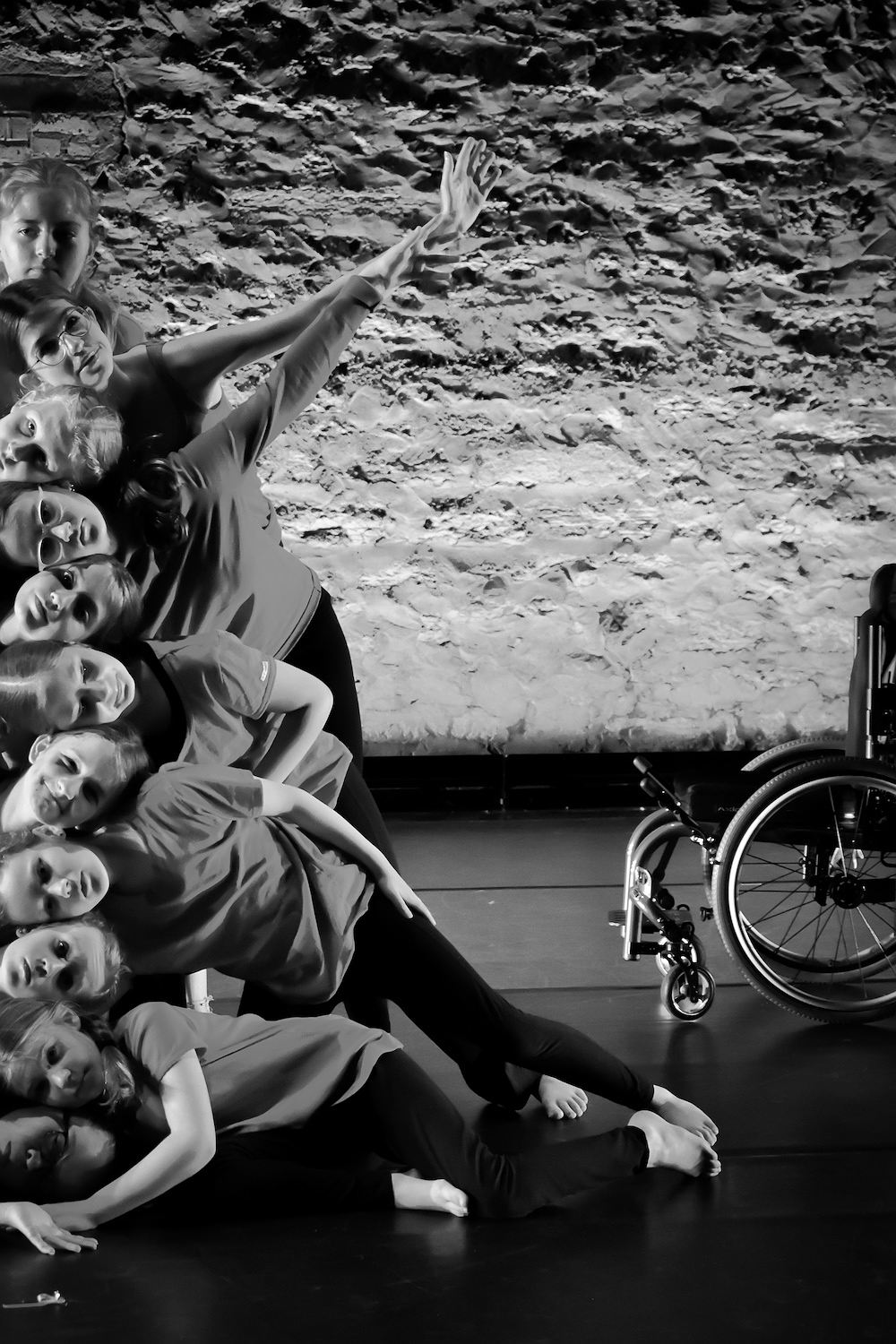 Dancers with stacked heads next to a wheelchair.