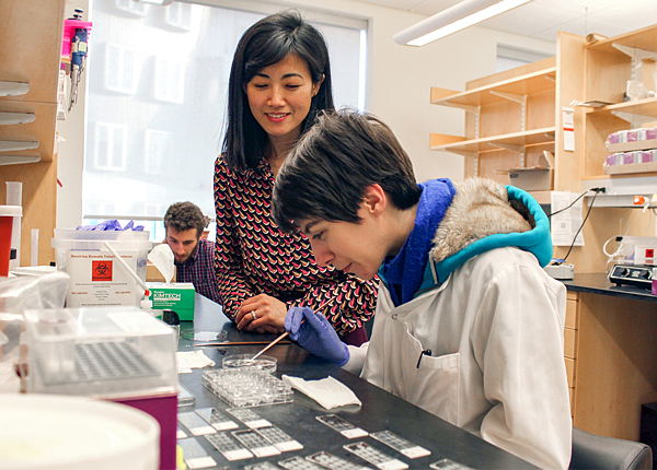 Student and professor inspect a petri dish in a laboratory