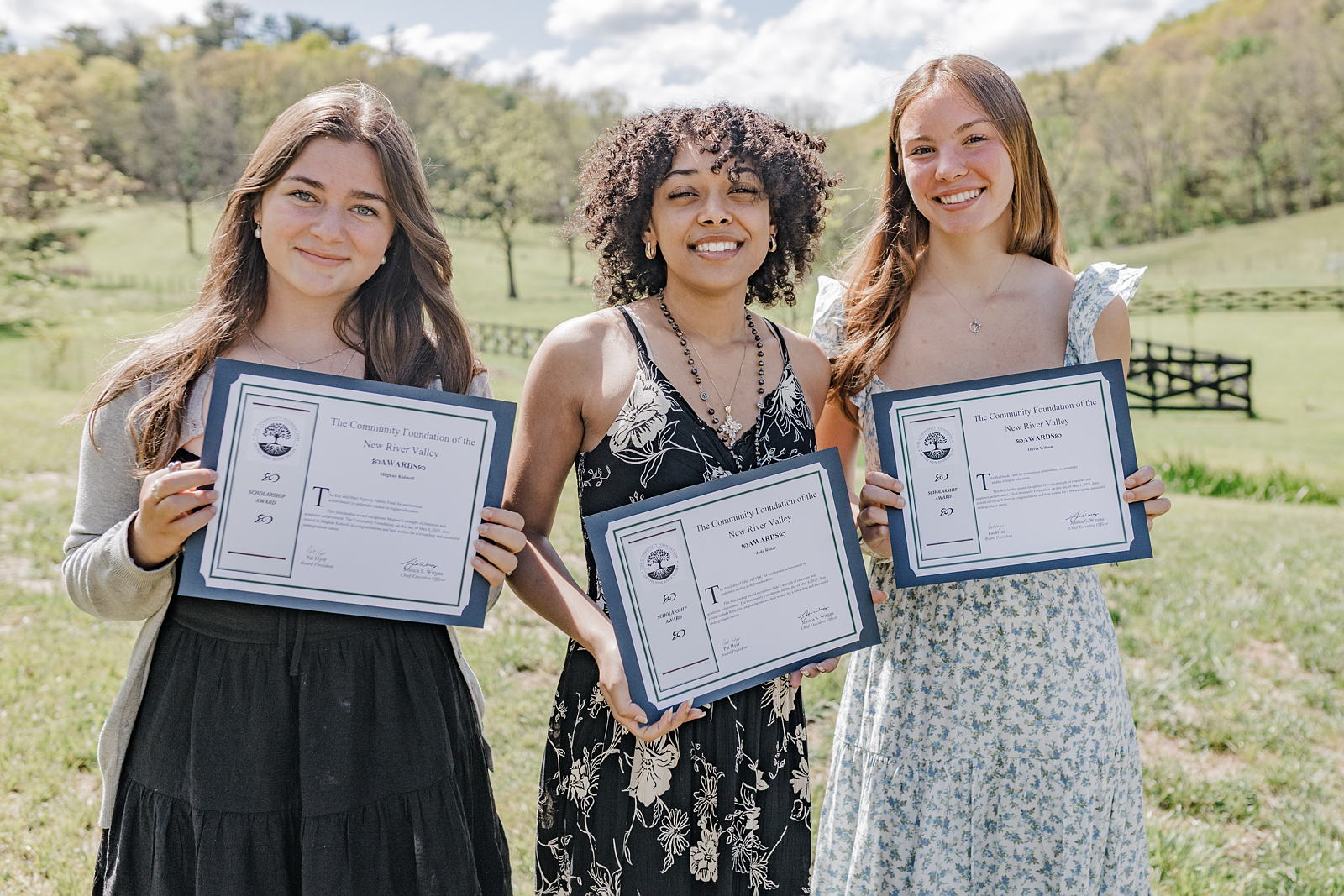 Three scholarship students hold their certificates at spring celebration