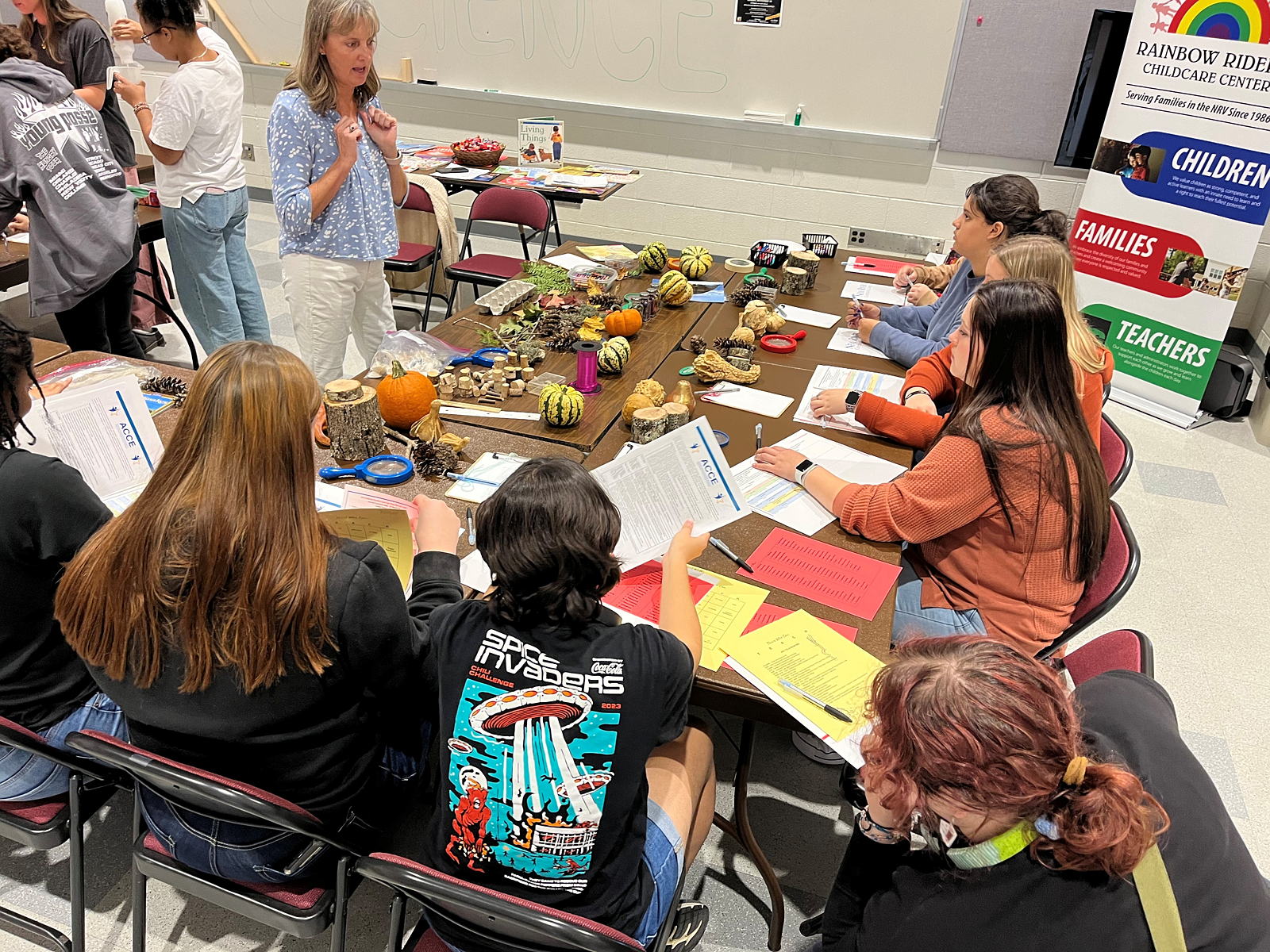 High schoolers sit around a table and listen to a talk from a childcare provider