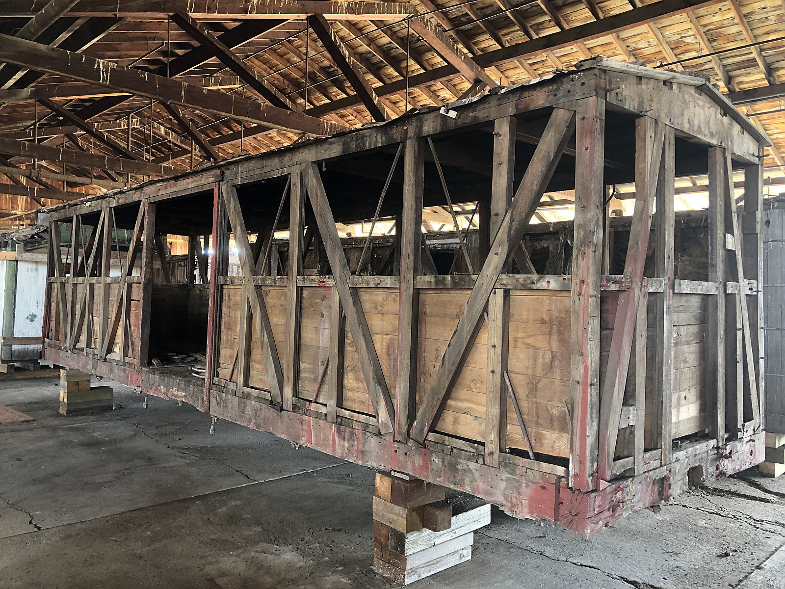Boxcar No. 518 with its exterior siding removed, revealing the timber frame and diagonal braces.