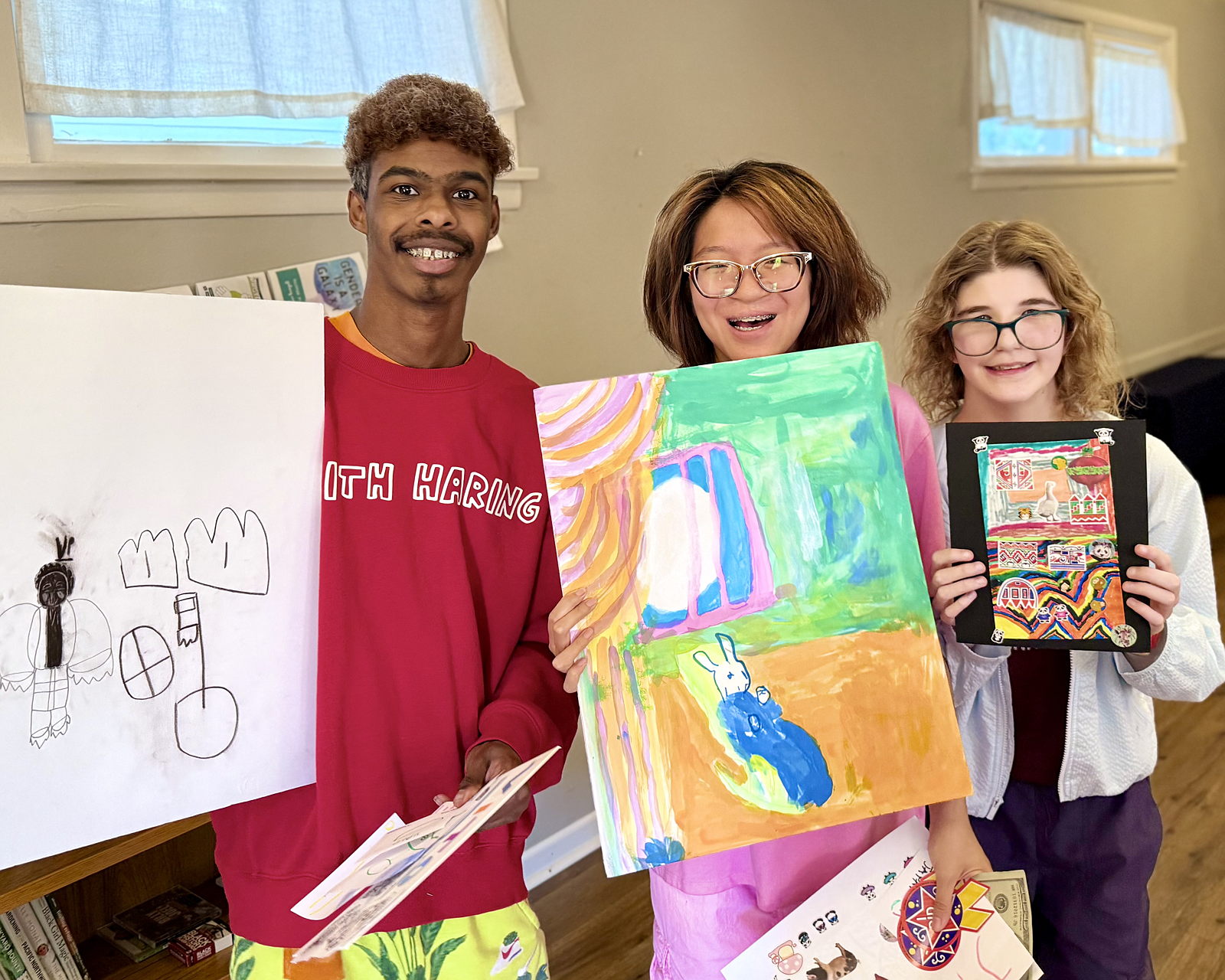 A group of three artists from the Olympia School District hold up their paintings and collages at the end of a studio session at Friendship Hall in Downtown Olympia, WA. 