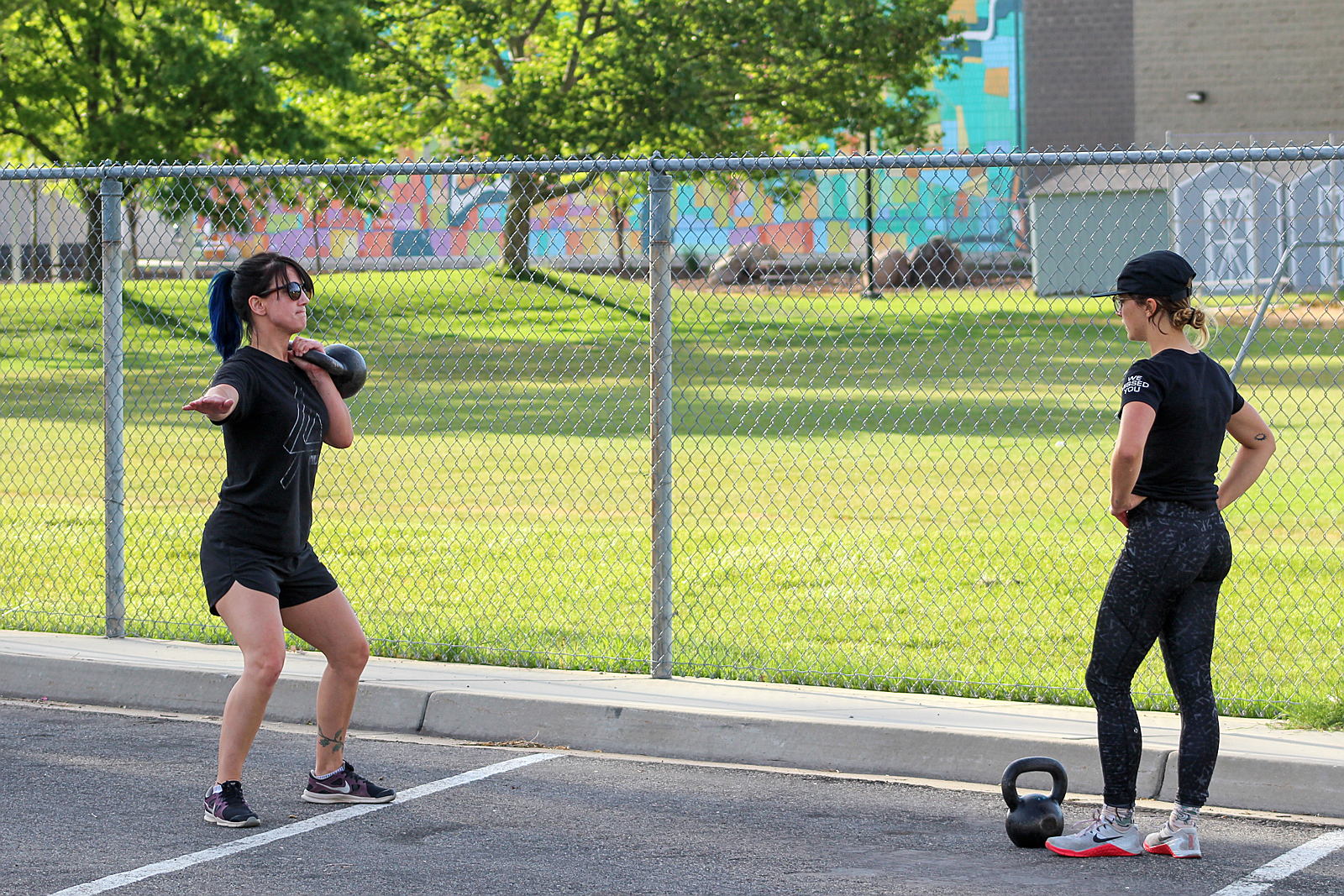 Two women with kettlebells, socially distant