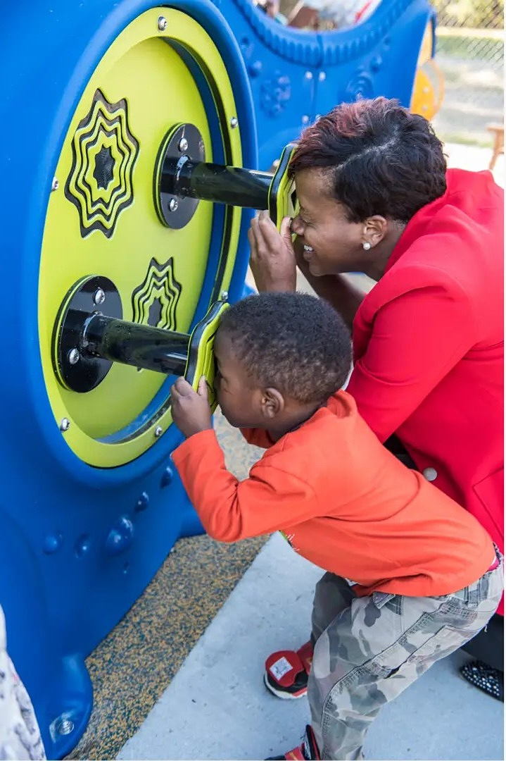 Mom and son look through scopes in lime green and bright blue play structure