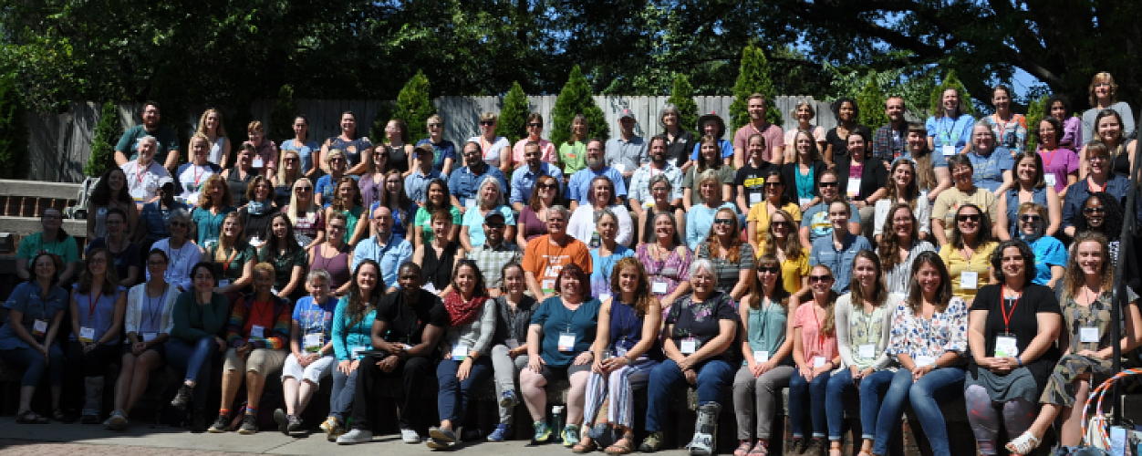 Over 100 educators from EENC's 2019 Annual Conference, sitting in an outdoor amphitheater.  
