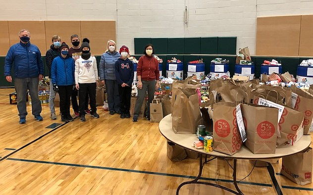 group of people standing next to food drive donations