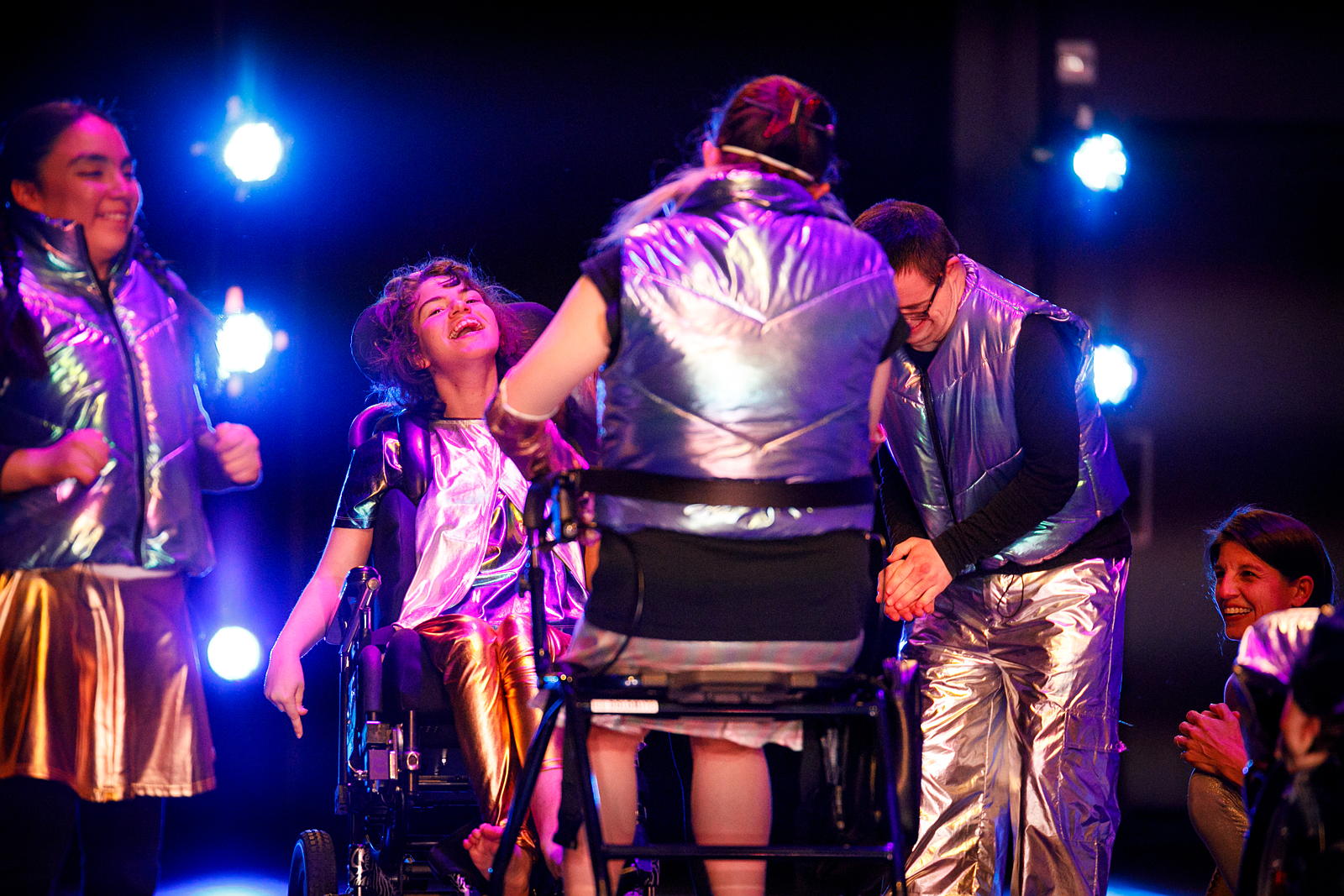 Dancers with wheelchairs and walkers laughing together. 
