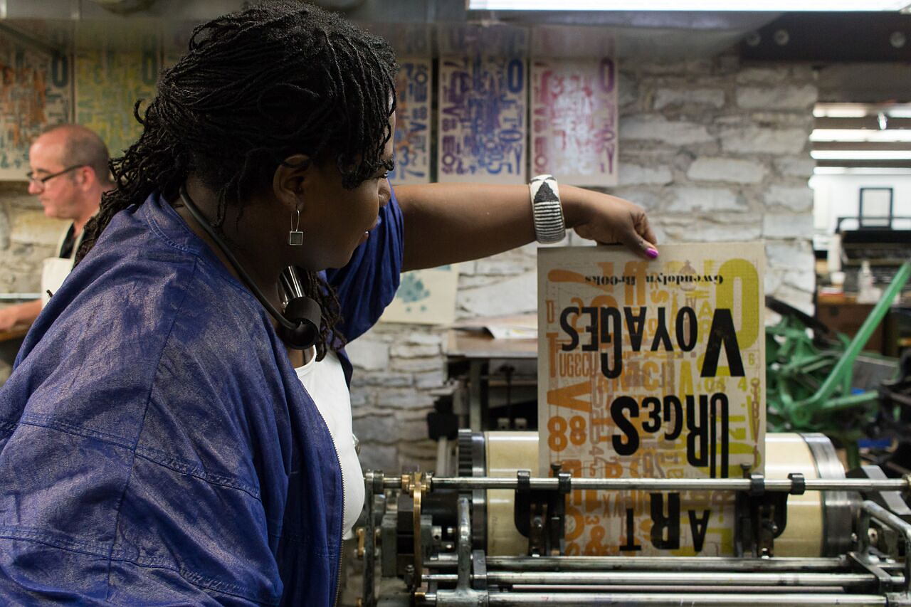 Community members and MCBA volunteers engaging in a letterpress printing demonstration at Wordplay.