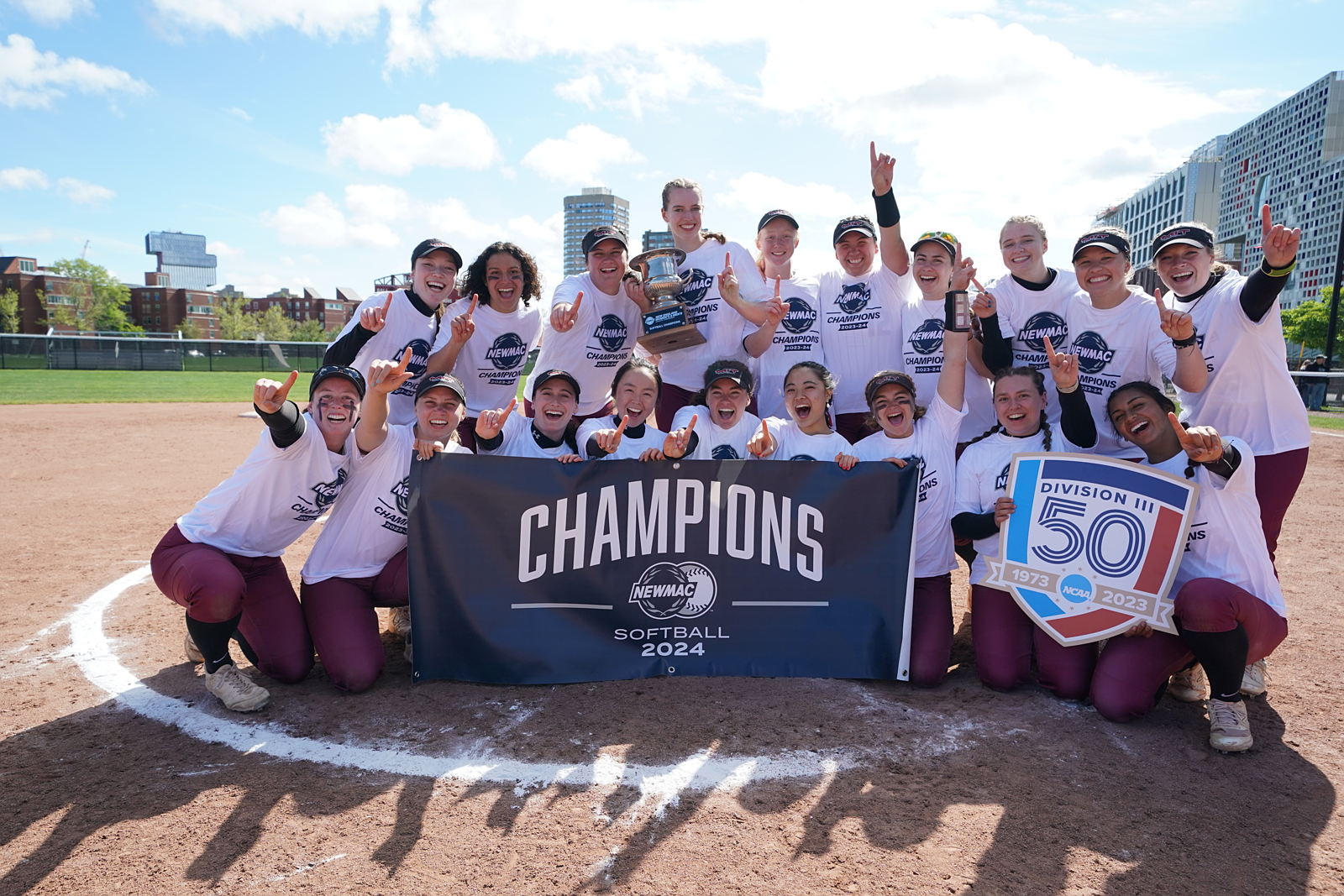 The MIT Softball team pose for a picture holding the 2024 Softball Championship banner