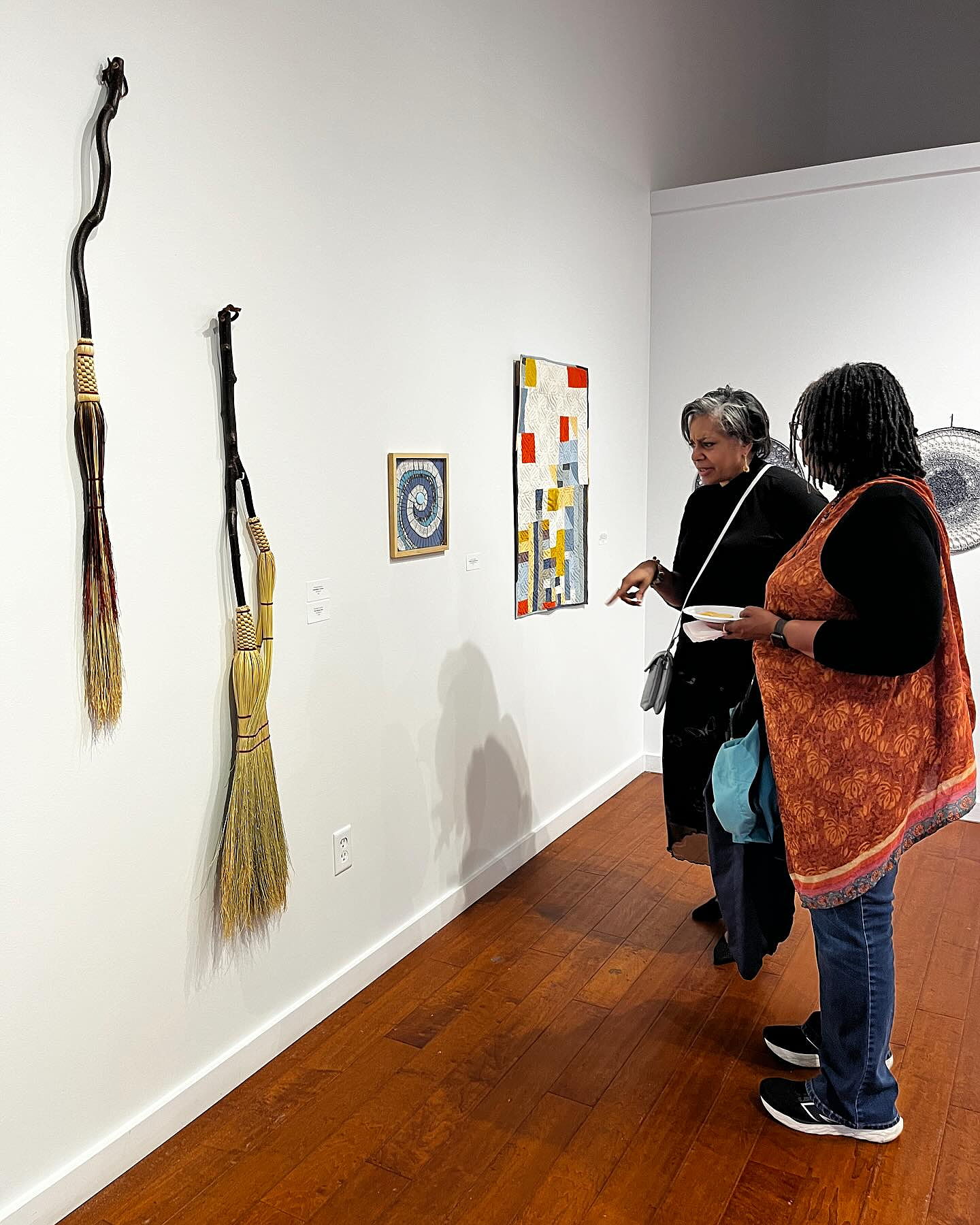 A man showing a woman his miniature city art piece. It sits a top a large table.
